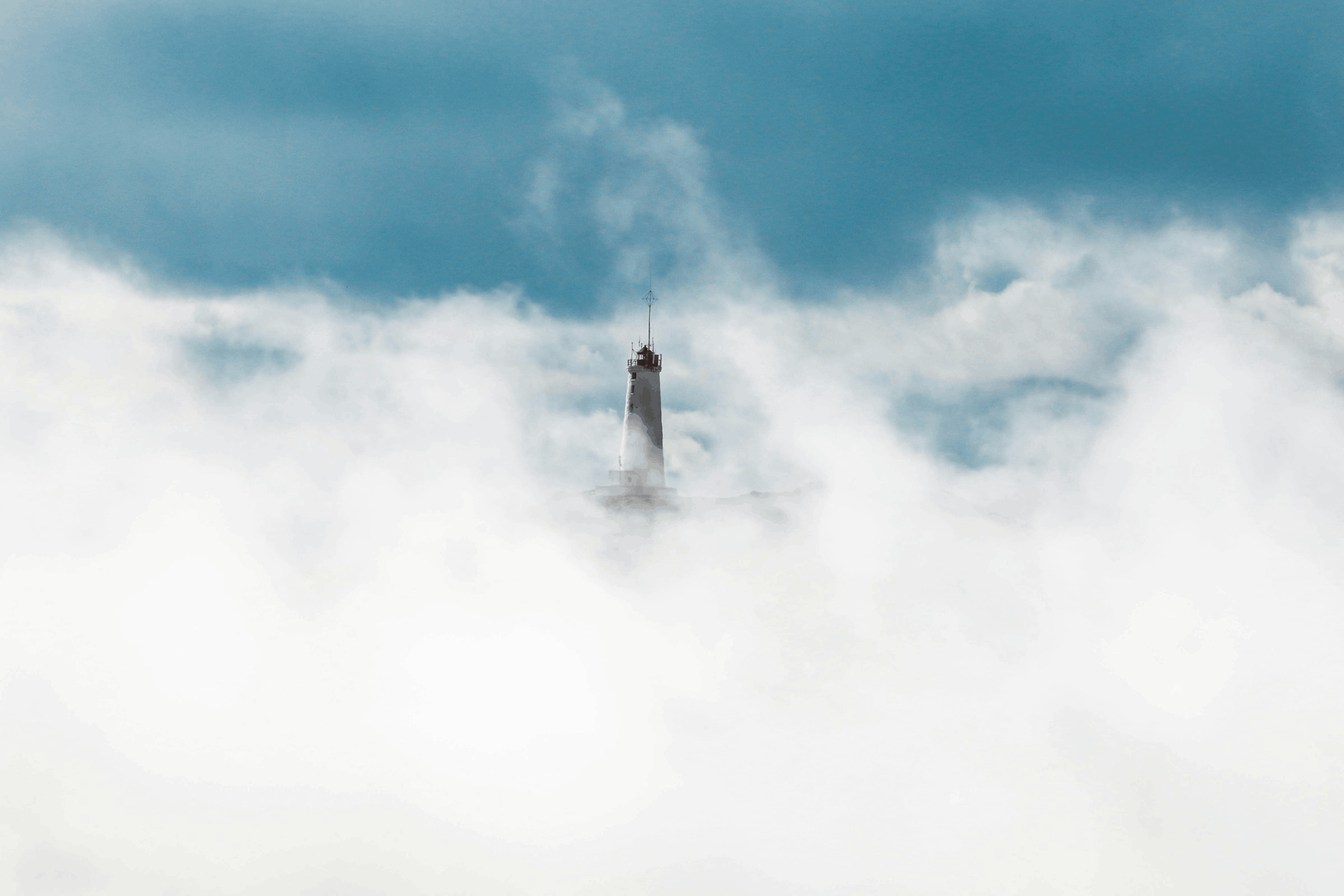Tower emerging through misty clouds and sky
